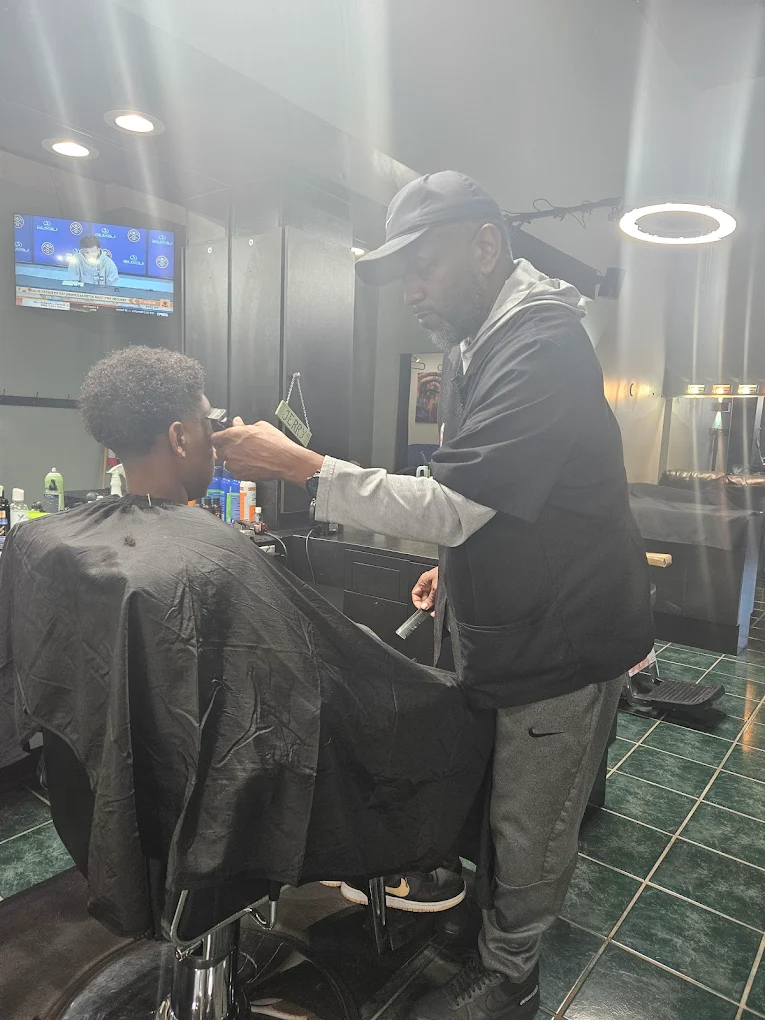 Ron Baggett styling a client's hair at Marveliz Cutz